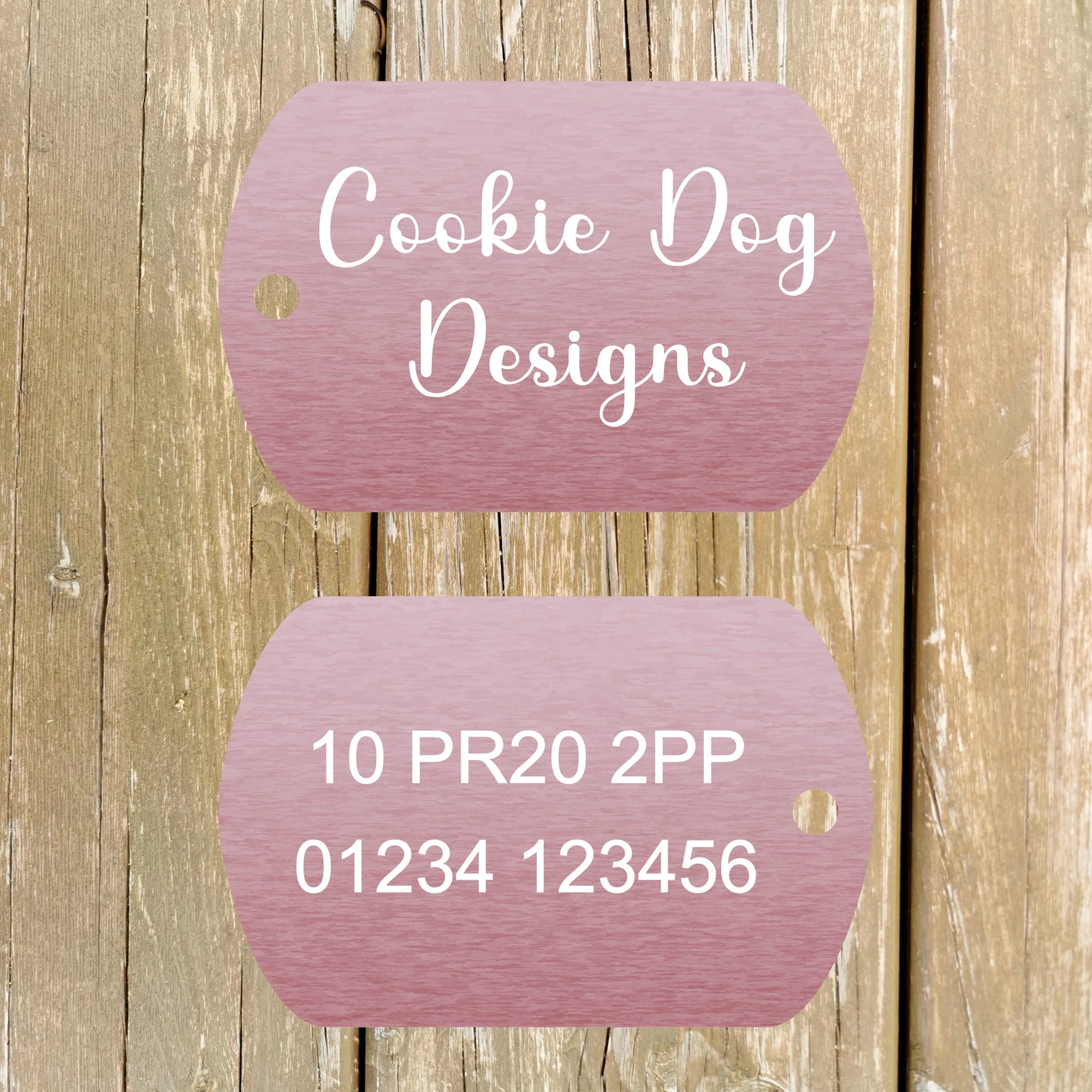Two pink tags with 'Cookie Dog Designs' text on a wooden background
