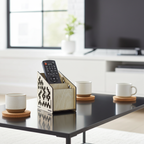 Wooden remote control holder on coffee table with cups and TV in background